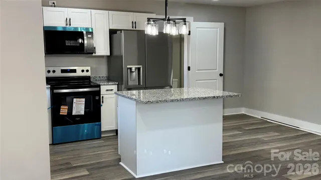 a kitchen with stainless steel appliances granite countertop a refrigerator a stove and a sink