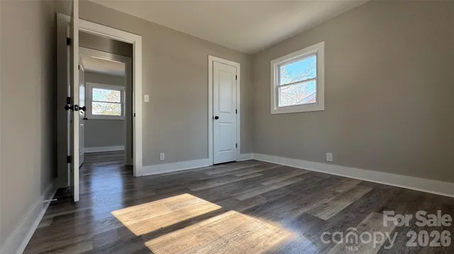 an empty room with wooden floor closet and windows