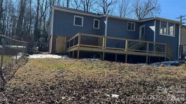 a backyard of a house with wooden fence and a large tree