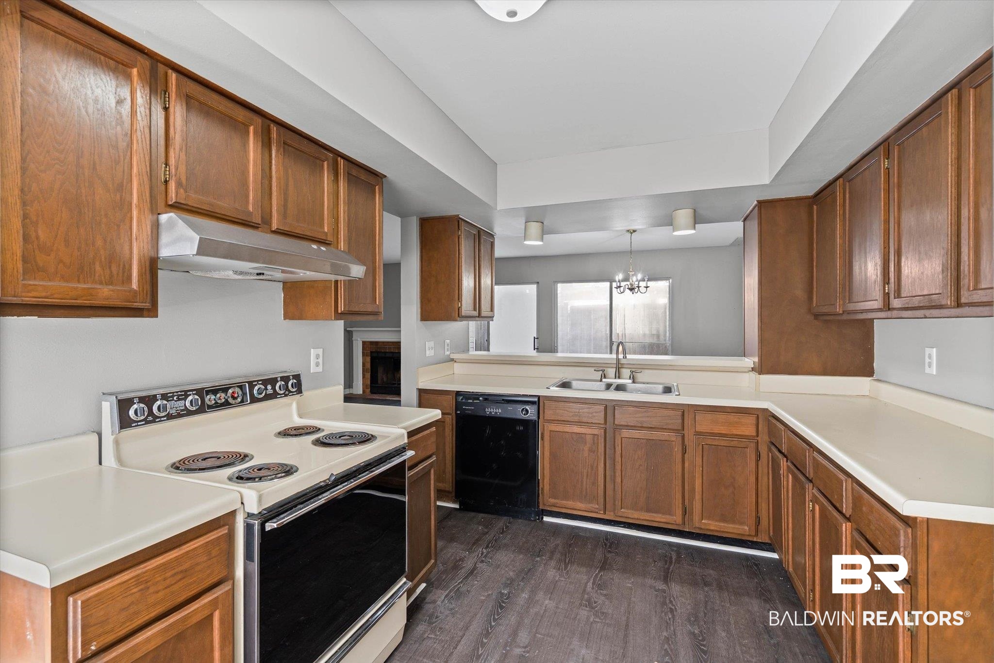 6701 Dickens Ferry Road, Unit 100 Mobile, AL 36608 - Photo 3 of 24 Kitchen with white range with electric stovetop, light countertops, a chandelier, dark wood-style floors, and brown cabinets