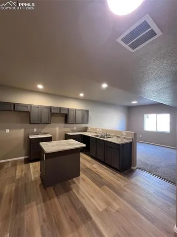 a large kitchen with a large counter top a sink and cabinets