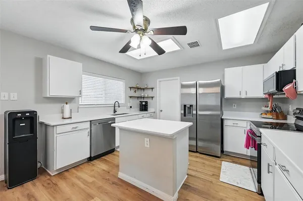 a kitchen with stainless steel appliances a sink a stove a refrigerator cabinets and a center island