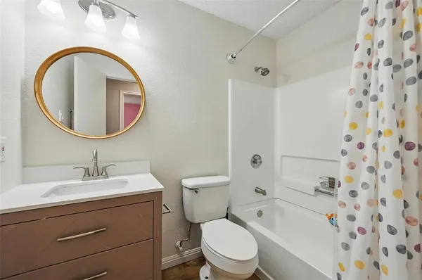 a bathroom with a toilet sink vanity tub and mirror