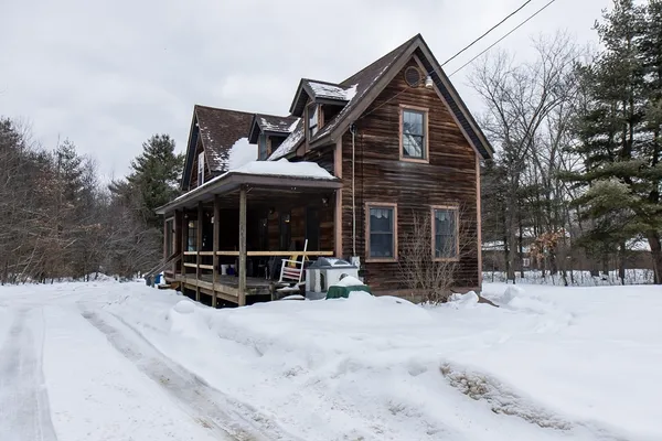 a view of house with yard outdoor seating and covered with snow