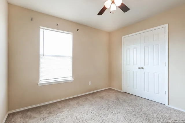 an empty room with a window and a ceiling fan