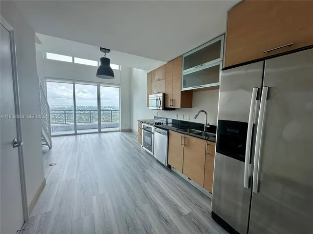 a kitchen with granite countertop a refrigerator a sink and wooden floor