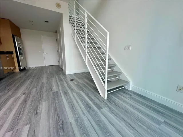 a view of a hallway with wooden floor and staircase