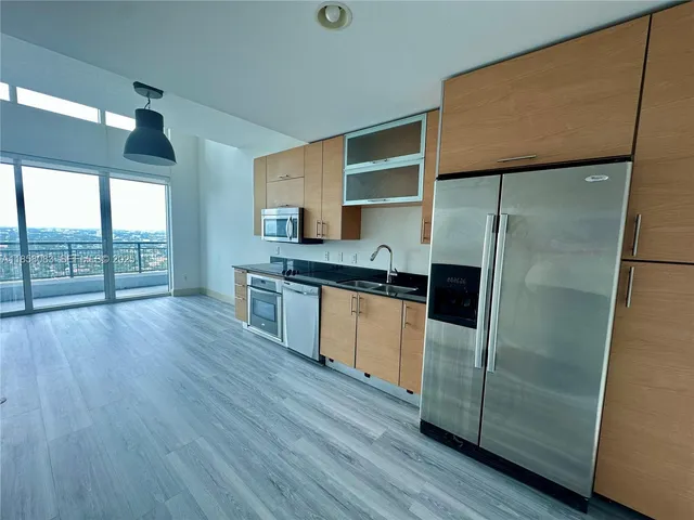 a kitchen with kitchen island wooden floors appliances and a counter top space