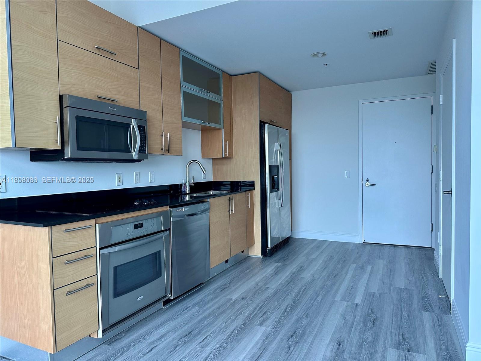 60 Southwest 13th Street, Unit 3207 Miami, FL 33130 - Photo 3 of 30 a kitchen with wooden floors and wooden cabinets