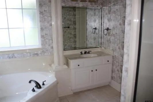 a bathroom with a tub sink and mirror