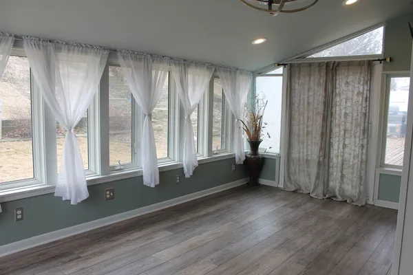 a view of an empty room with a window and wooden floor