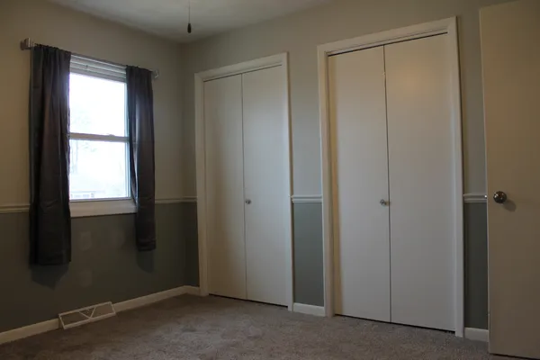 an empty room with a ceiling fan and window