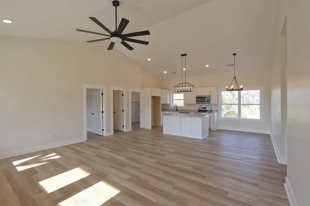 a view of empty room with wooden floor and ceiling fan