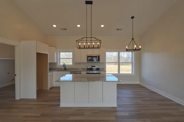 a kitchen with stainless steel appliances granite countertop a stove a refrigerator and a wooden floor