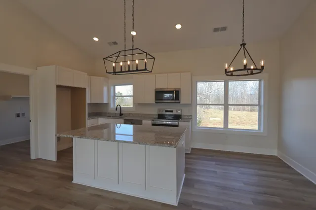 a kitchen with stainless steel appliances granite countertop a stove top oven a refrigerator a sink dishwasher and a fireplace with wooden floor