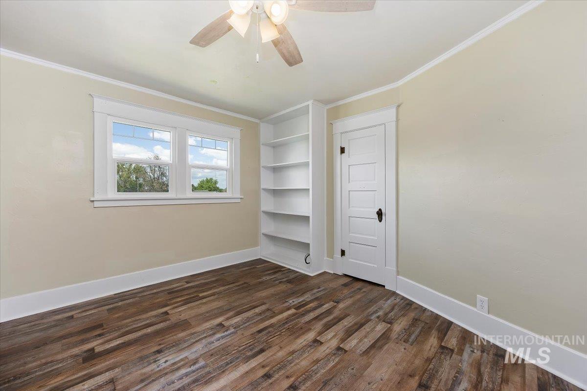 813 7th Street Rupert, ID 83350 - Photo 36 of 48 Room featuring wood-finish flooring, a ceiling fan, a built-in bookshelf, and a multi-pane window with white trim