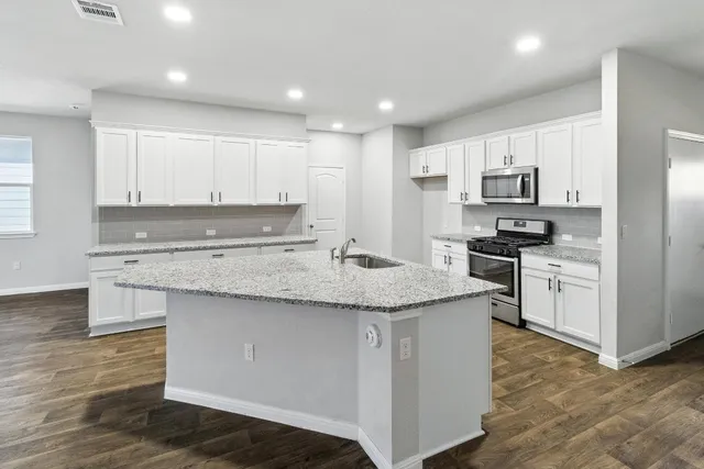 a kitchen with granite countertop a sink stove top oven and cabinets
