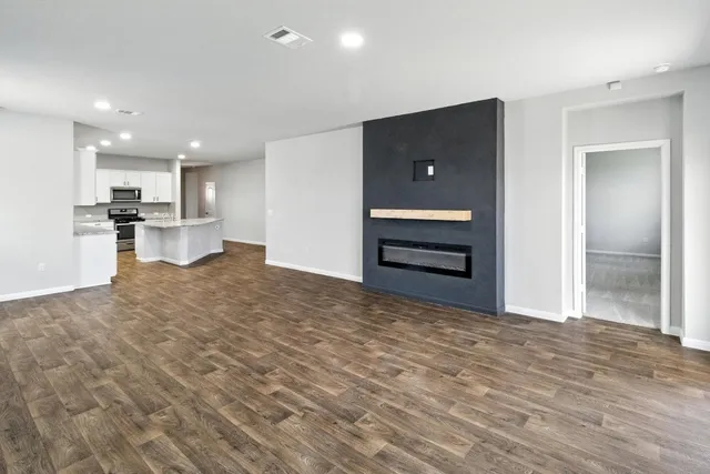 a view of kitchen and empty room with wooden floor