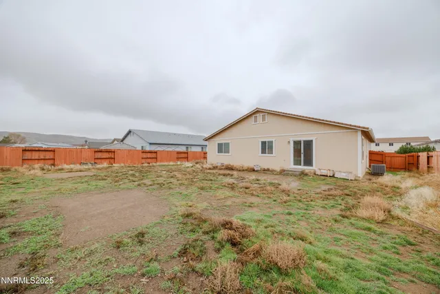 a view of backyard of house with wooden fence