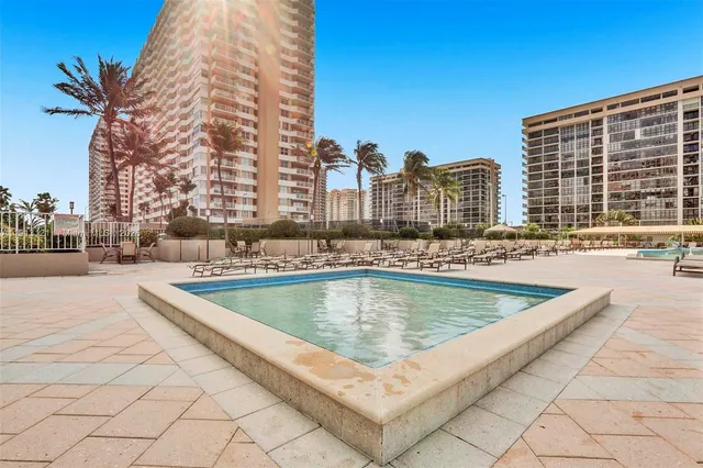 a view of swimming pool with outdoor seating and buildings in the background