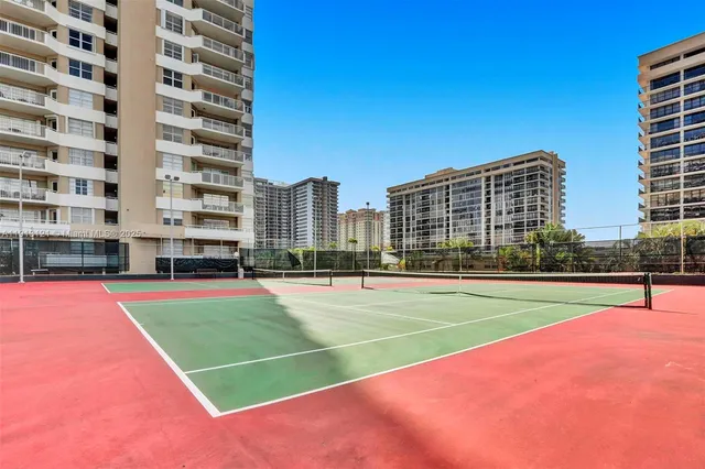 a view of tennis court with a large building