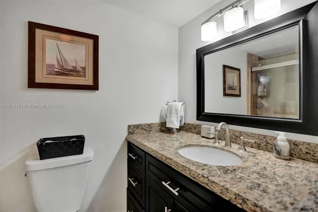 a bathroom with a granite countertop sink vanity and toilet