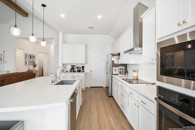 a large white kitchen with a large stove top oven a sink a counter space and cabinets