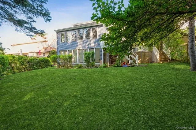 a view of a brick house with a big yard and large trees