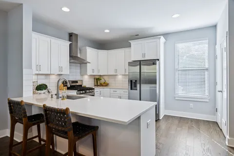 a kitchen with stainless steel appliances white cabinets a sink a stove and a refrigerator