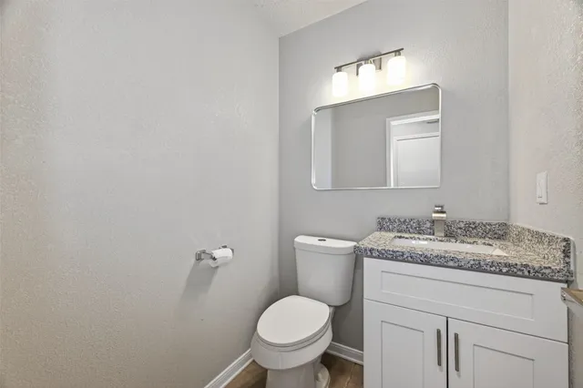 a bathroom with a granite countertop toilet sink and mirror