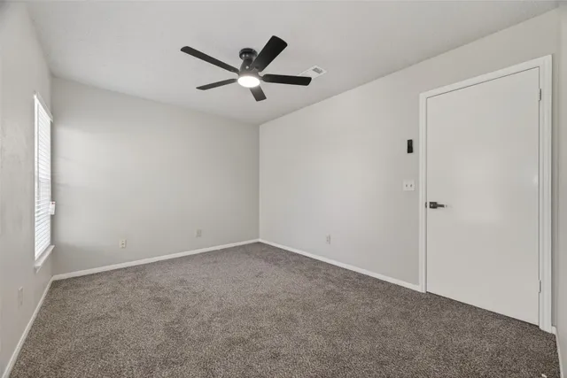 an empty room with a ceiling fan and window