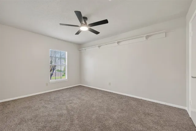 a view of an empty room with a ceiling fan and window