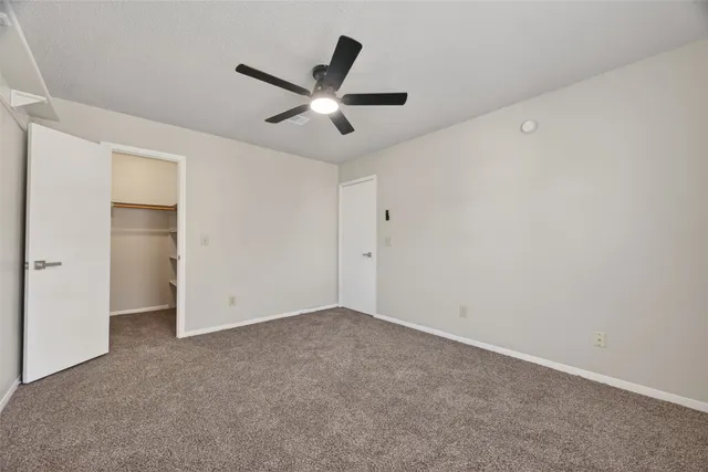 an empty room with ceiling fan and window