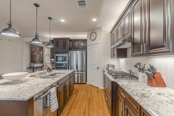 a kitchen with stainless steel appliances granite countertop a sink a stove and a wooden floors