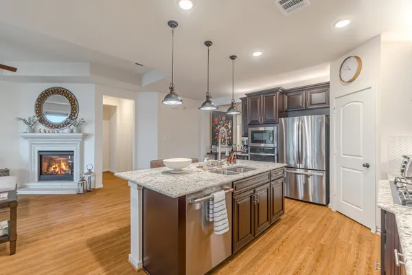 a kitchen with stainless steel appliances granite countertop a wooden cabinets a stove a sink and a wooden floors