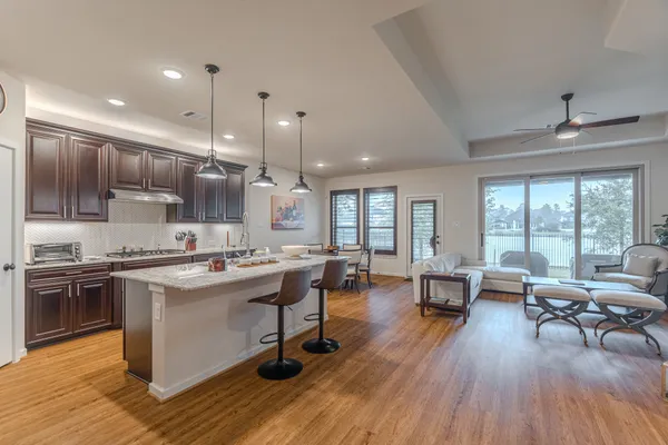 a open kitchen with stainless steel appliances granite countertop a stove and chairs with wooden floors
