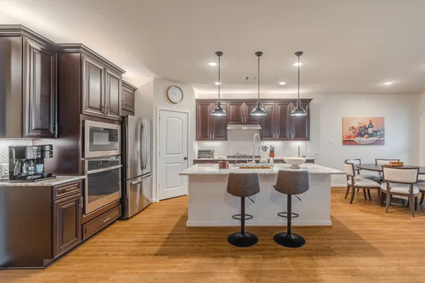 a view of a kitchen with kitchen island stainless steel appliances refrigerator stove dining table and chairs