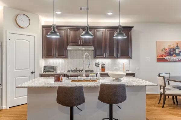 a kitchen with stainless steel appliances granite countertop a sink a stove and chairs with wooden floor