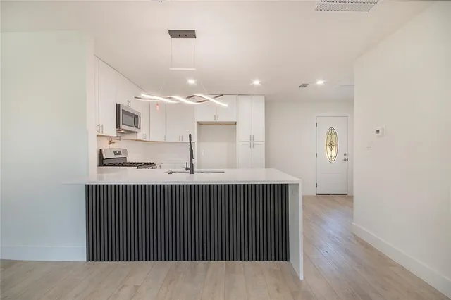 a kitchen with kitchen island a sink stainless steel appliances and cabinets