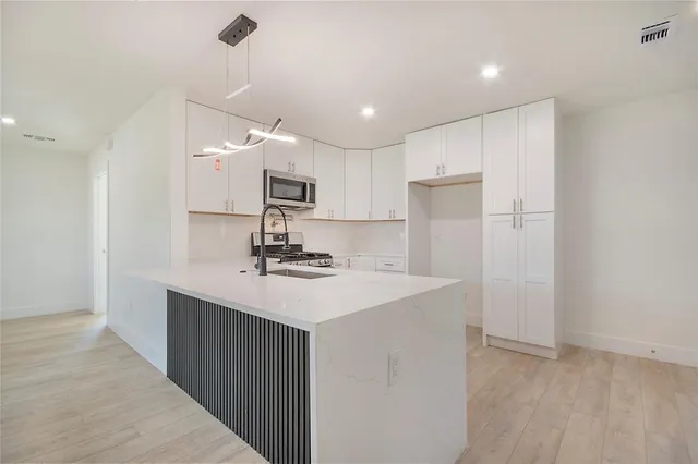a kitchen with kitchen island a sink stainless steel appliances and cabinets