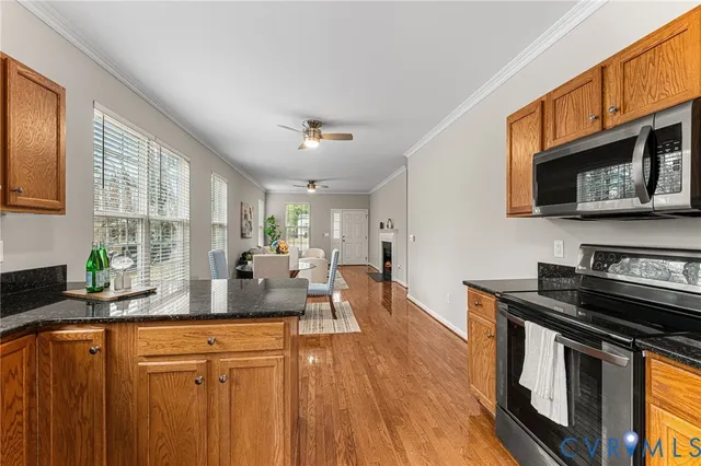 a kitchen with stainless steel appliances granite countertop a stove a sink dishwasher and a microwave oven with wooden floor