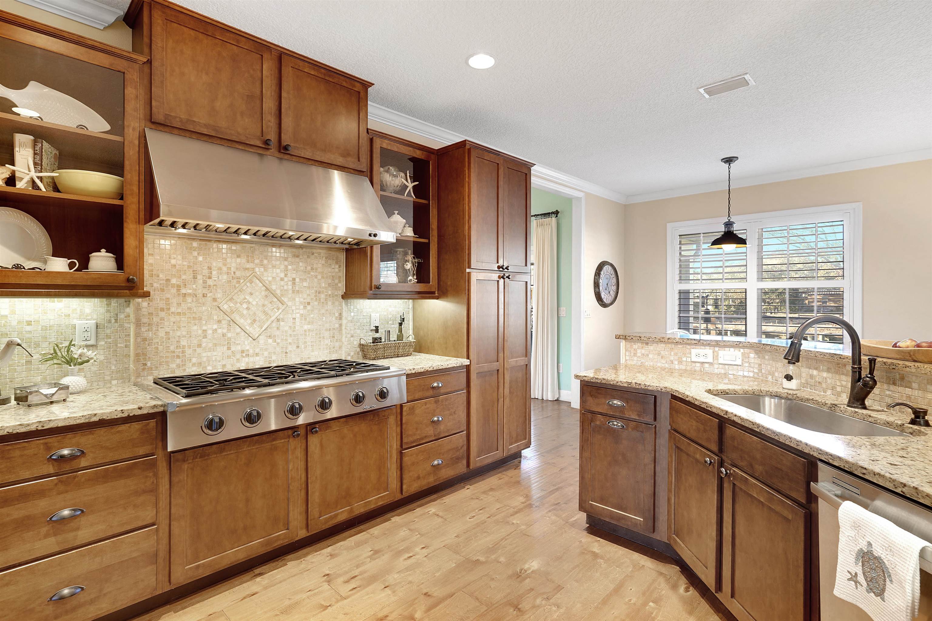 248 Pizarro Road St. Augustine, FL 32080 - Photo 13 of 53 Kitchen featuring light stone countertops, stainless steel appliances, wood finish cabinetry, crown molding, and light wood-style floors