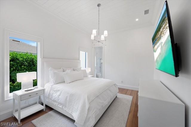 6285 Highcroft Drive Naples, FL 34119 - Photo 39 of 50 a bedroom with a large bed and a chandelier