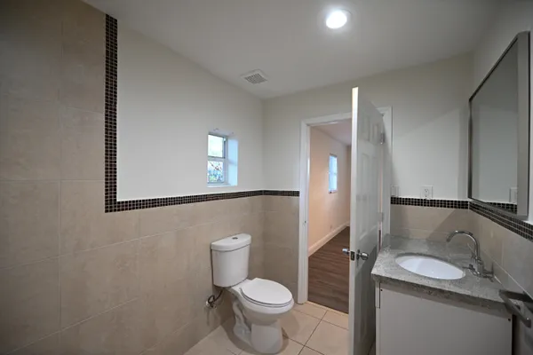 a bathroom with a granite countertop toilet sink and mirror