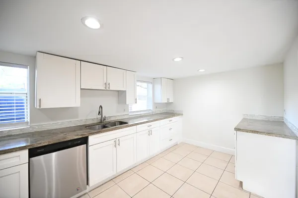 a kitchen with a sink dishwasher and white cabinets with wooden floor