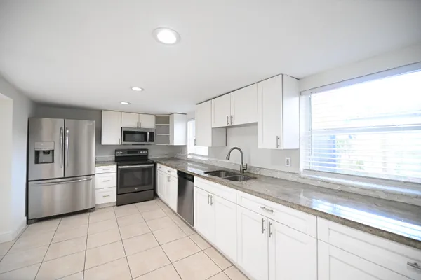 a kitchen with stainless steel appliances granite countertop a sink a stove a refrigerator and cabinets