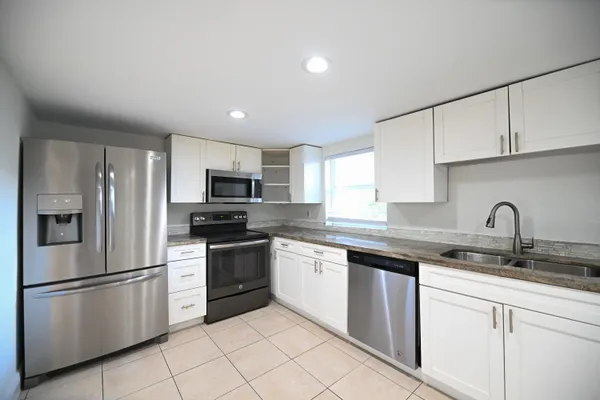 a kitchen with stainless steel appliances granite countertop a refrigerator sink and stove