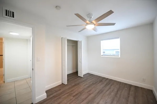 an empty room with wooden floor and a ceiling fan
