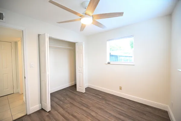 an empty room with wooden floor and a ceiling fan