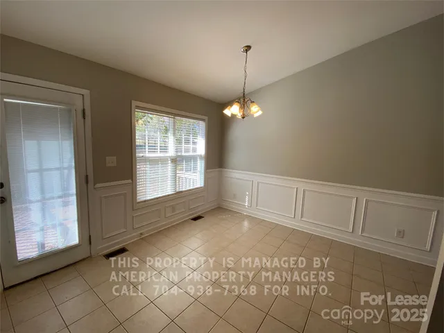 a view of an empty room with window and chandelier fan